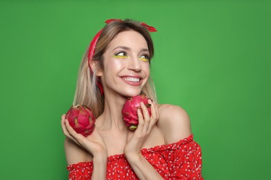 Photo of Young woman with fresh pitahayas on green background. Exotic fruits