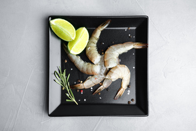 Photo of Fresh raw shrimps with lime and rosemary on light grey table, top view