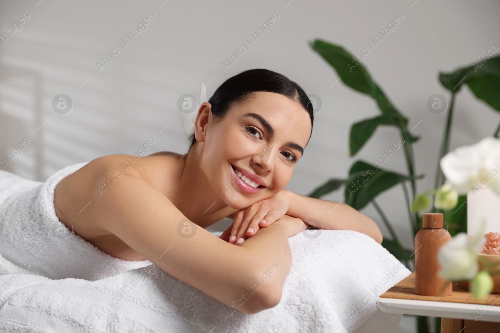 Photo of Beautiful happy woman relaxing on massage table in spa salon