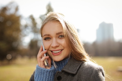 Portrait of beautiful young woman talking on phone in city park