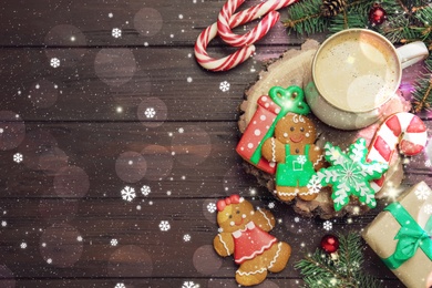 Decorated Christmas cookies and cup of delicious drink on wooden table, flat lay. Space for text