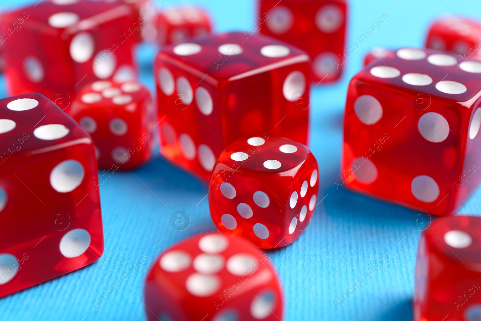 Photo of Many red game dices on light blue background, closeup