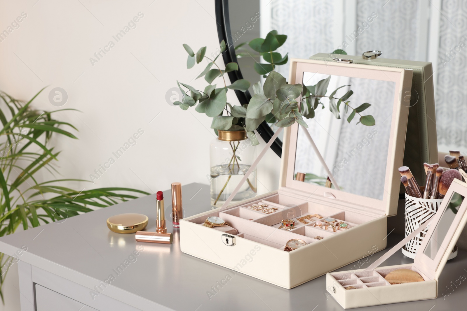 Photo of Elegant jewelry boxes with expensive wristwatches and beautiful bijouterie on grey table in room