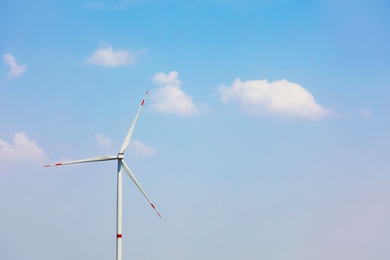 Photo of Modern wind turbine against blue sky. Energy efficiency