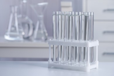 Photo of Test tubes with transparent liquid on table in laboratory. Space for text