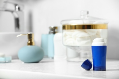 Photo of Stick deodorant and different toiletry on table in bathroom, space for text