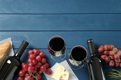 Flat lay composition with red wine and snacks on blue wooden table, space for text