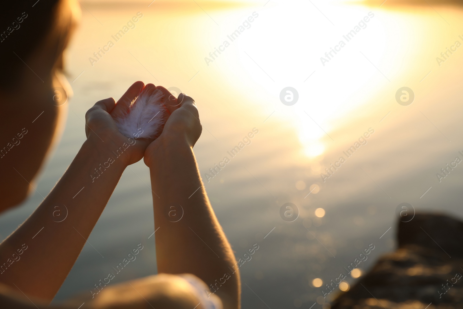 Photo of Woman with feather outdoors on sunset, closeup. Healing concept