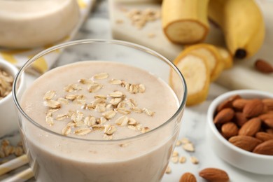 Glass of tasty banana smoothie with oatmeal on table, closeup