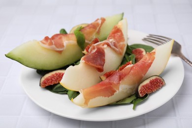 Tasty melon, jamon and figs on white tiled table, closeup