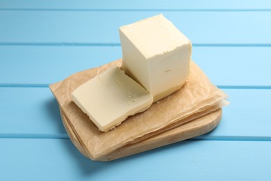 Block of tasty butter on light blue wooden table