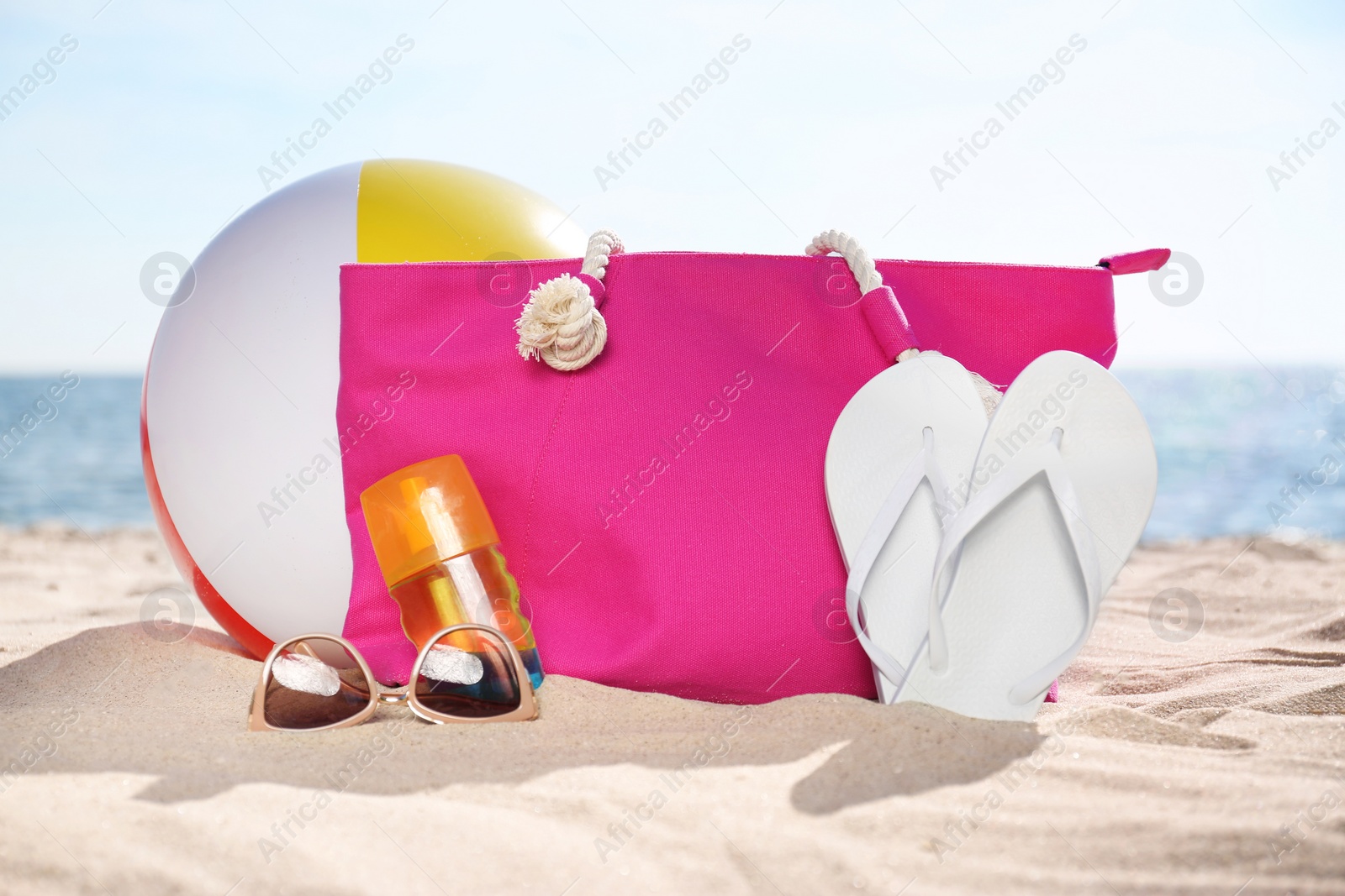 Photo of Bag and beach objects on sand near sea