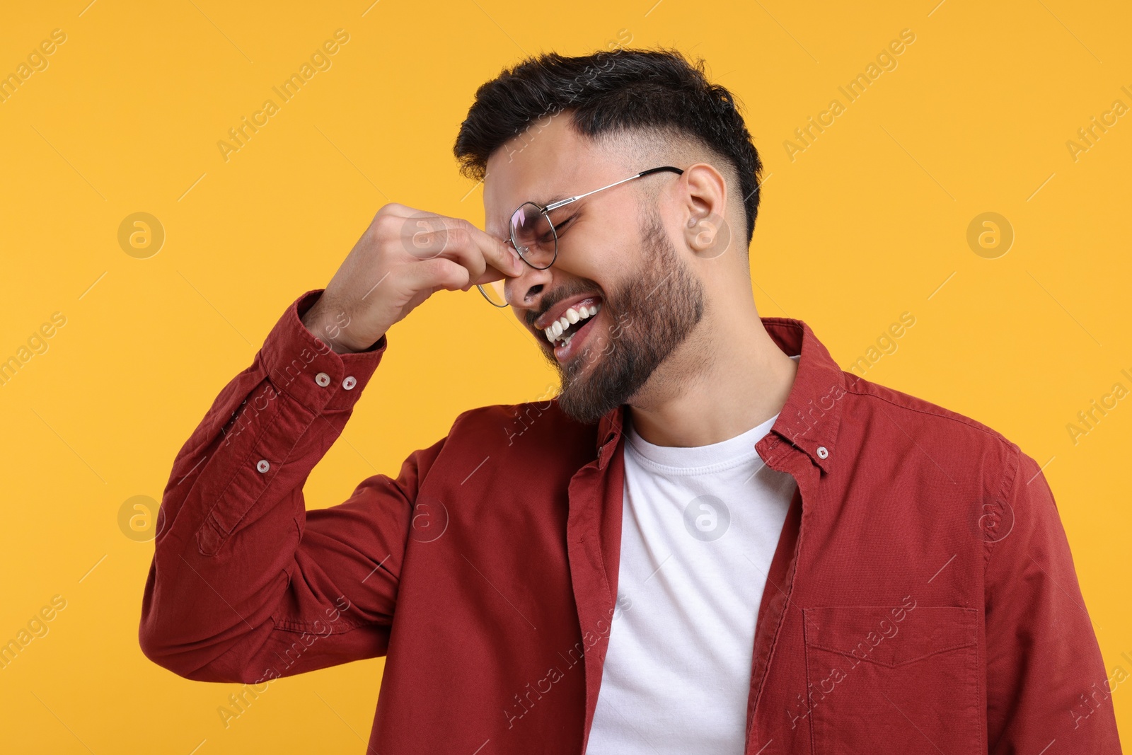 Photo of Handsome young man laughing on yellow background