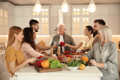 Happy people cooking food together in kitchen