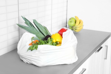 Photo of Plastic shopping bag full of vegetables on countertop in kitchen