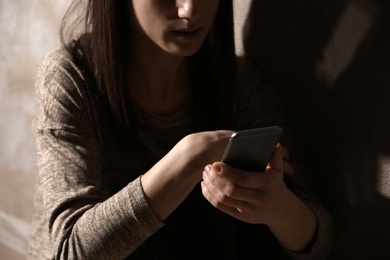 Photo of Woman using smartphone in dark room, closeup. Loneliness concept
