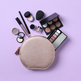 Photo of Cosmetic bag with makeup products on violet background, flat lay