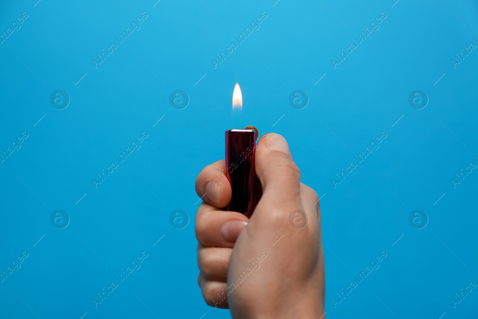 Photo of Woman holding black lighter on light blue background, closeup