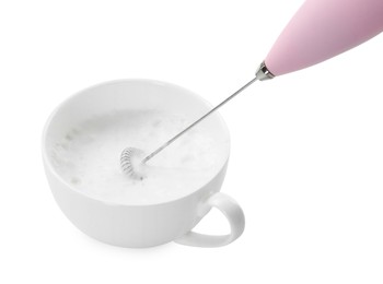 Photo of Whisking milk in cup with mini mixer (frother wand) isolated on white, closeup