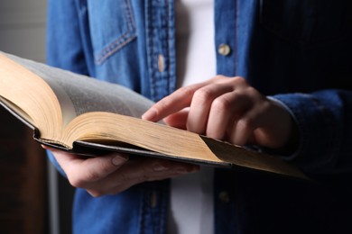 Woman reading old holy Bible on blurred background, closeup