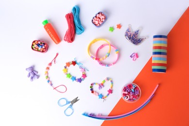 Photo of Kid's handmade beaded jewelry and different supplies on color background, flat lay