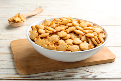 Photo of Delicious goldfish crackers in bowl on white wooden table
