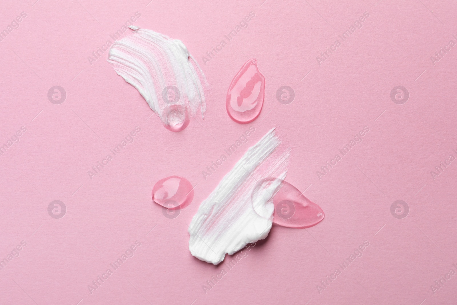 Photo of Samples of cosmetic gel and cream on pink background, top view