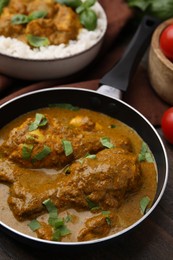 Photo of Delicious chicken with curry sauce served on wooden table, closeup