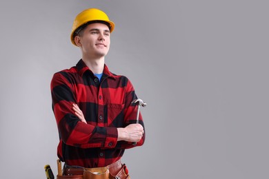 Photo of Professional repairman holding hammer on light grey background. Space for text