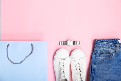 Photo of Stylish flat lay composition with shopping bag and clothes on color background