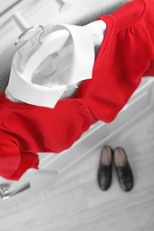 Photo of Shirt and jumper on hanger over pair of shoes indoors, above view. School uniform