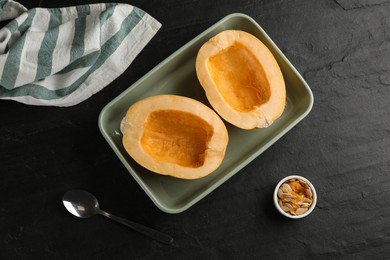 Photo of Halves of fresh spaghetti squash in baking dish on black table, flat lay. Cooking at home