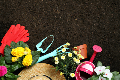 Flat lay composition with gardening tools and flowers on soil, space for text