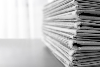 Stack of newspapers on grey table, space for text. Journalist's work