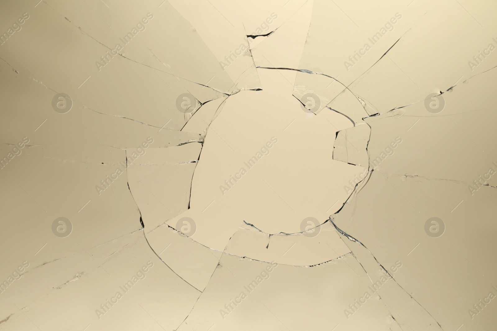 Photo of Closeup view of broken glass with cracks on beige background