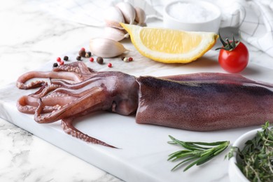 Photo of Fresh raw squid served on white marble table, closeup