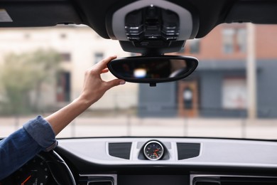 Photo of Woman adjusting rear view mirror inside her car, closeup
