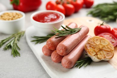 Delicious vegetarian sausages with rosemary and vegetables on grey table, closeup