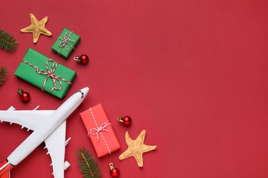 Flat lay composition with toy airplane, gift boxes and space for text on red background. Christmas vacation