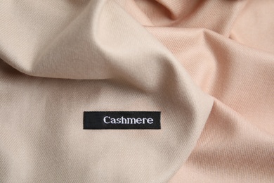 Photo of Warm beige cashmere garment with clothing label, closeup