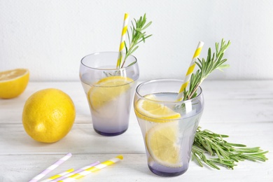 Tasty refreshing lemon cocktail with rosemary on table