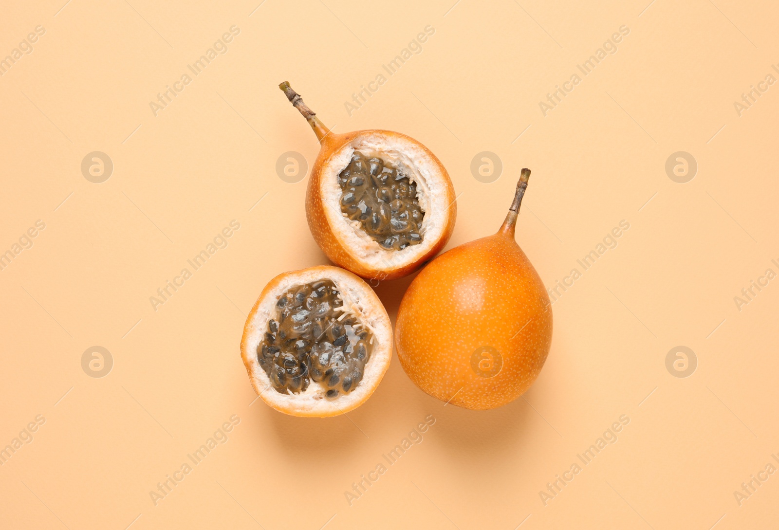 Photo of Delicious ripe granadillas on beige background, flat lay