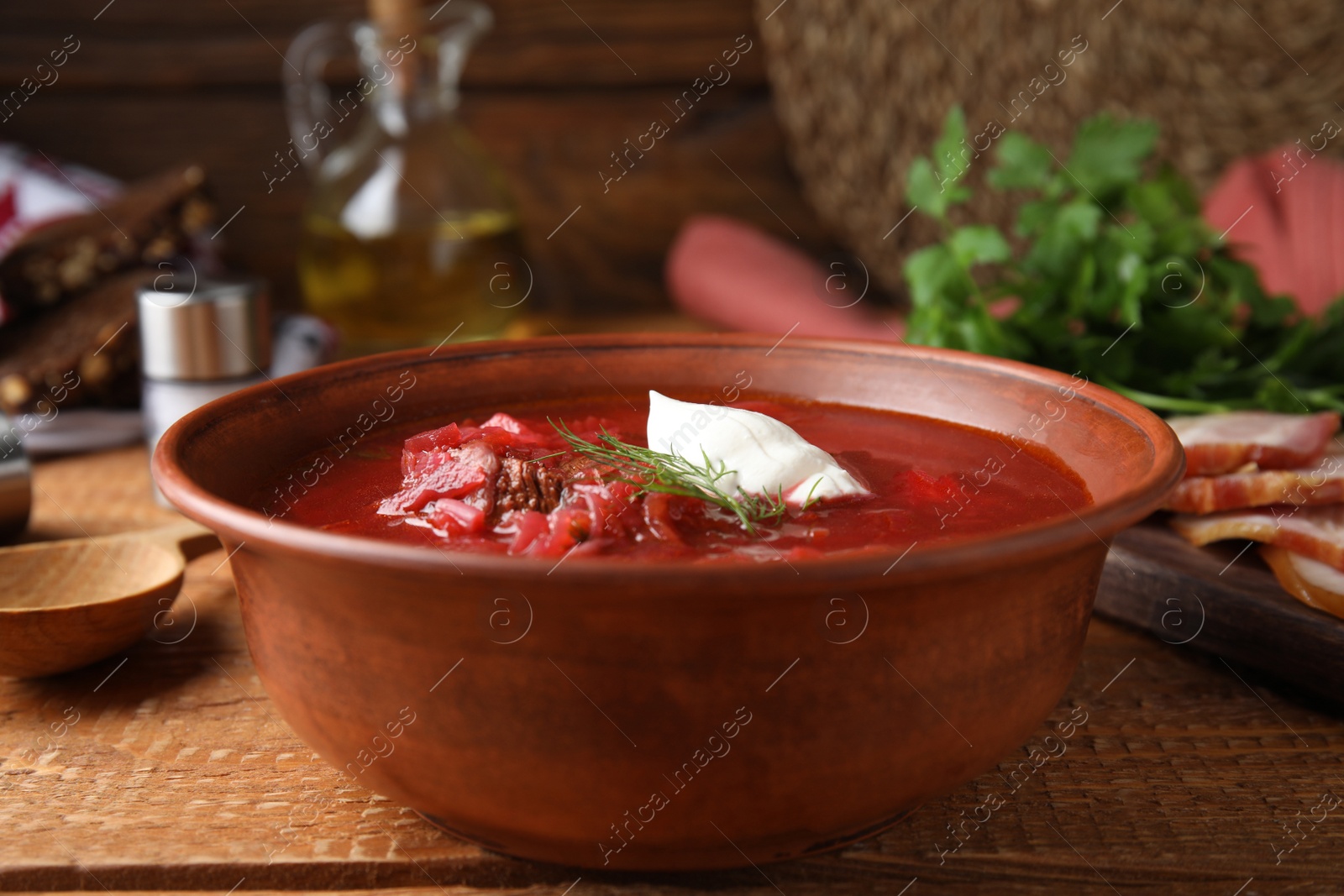 Photo of Clay bowl with Ukrainian borsch served on wooden table