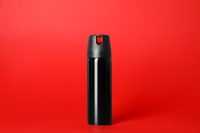 Photo of Bottle of gas pepper spray on red background