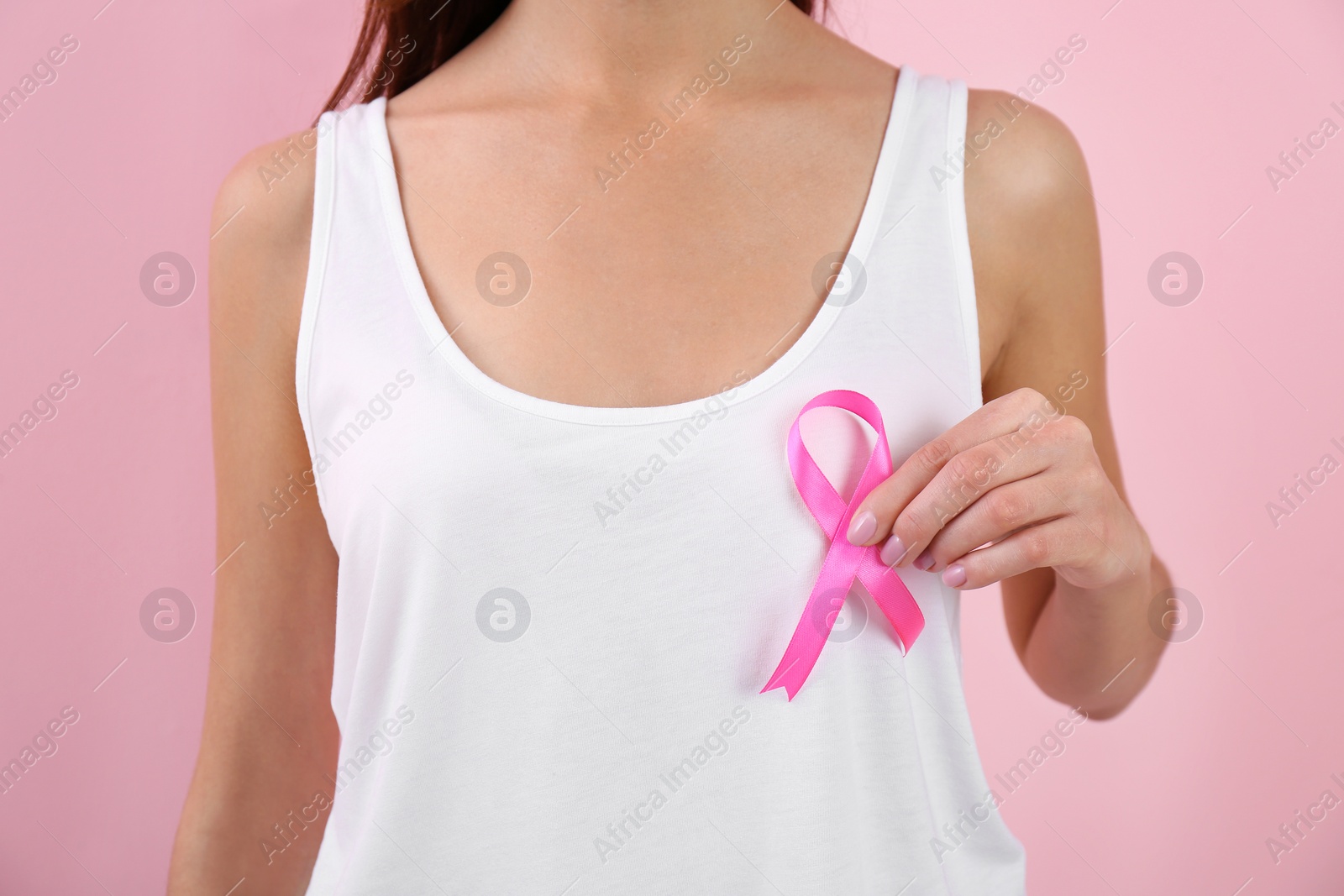 Photo of Woman holding pink ribbon on color background, closeup. Breast cancer awareness