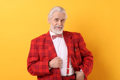 Photo of Portrait of grandpa with stylish red suit and bowtie on yellow background
