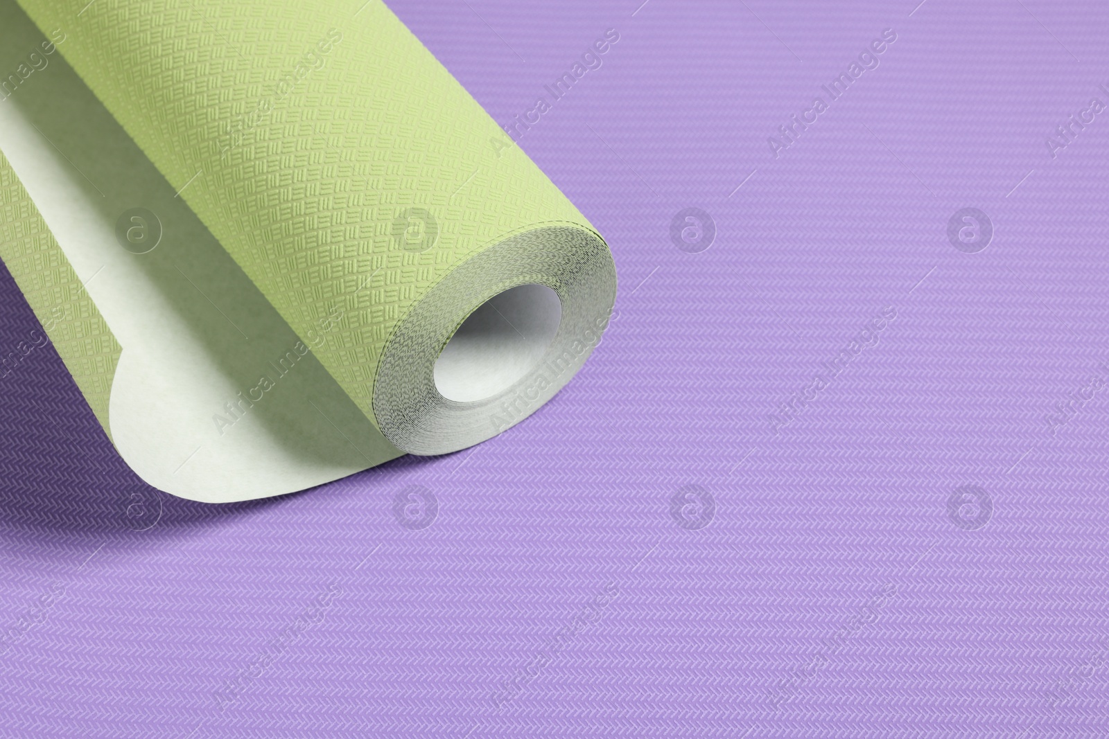 Photo of One green wallpaper roll on violet sample, space for text