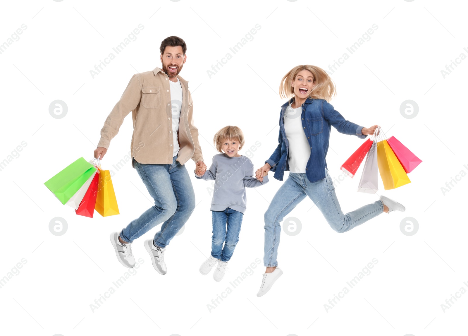 Photo of Family shopping. Happy parents and son jumping with many colorful bags on white background