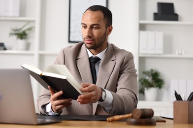 Photo of Serious lawyer reading book at table in office