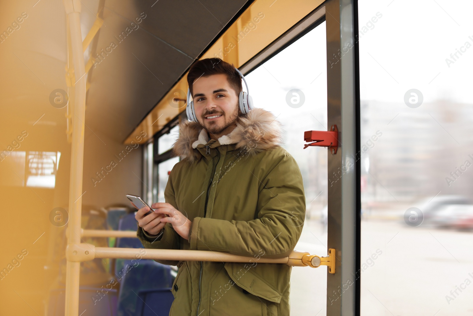 Photo of Young man listening to music with headphones in public transport